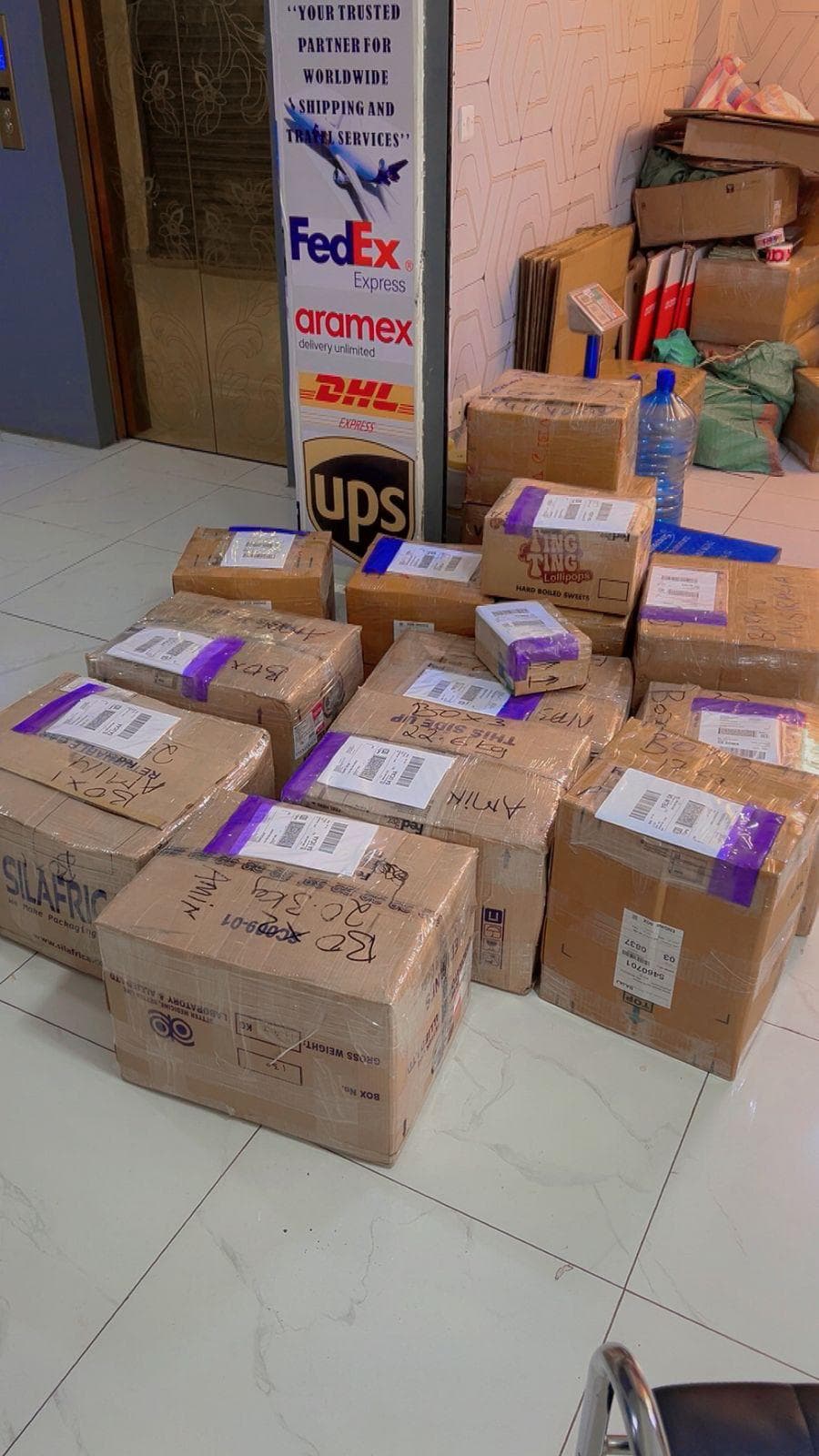 Packed and labeled shipments on the Skyzone depot floor beside the courier partner display